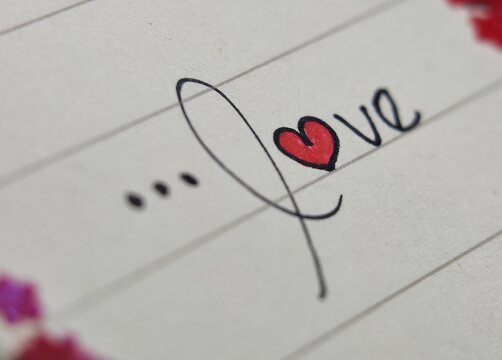 Handwritten red heart symbol in cursive script on elegant romantic notebook paper. Perfect for valentines day card designs or lovethemed graphics.