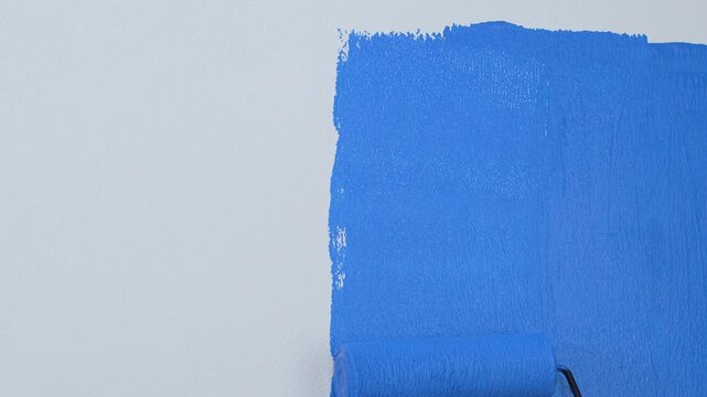 Roller Brush Painting, Worker painting on surface wall Painting apartment, renovating with blue color paint. Leave empty copy space white to write descriptive text beside.	
