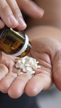 close up woman hand holding a medicine, with pours the pills out of medicine bottle. Stop drug use Taking Medication Caring for the health care medical concept.	
