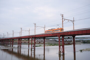 Obraz premium OSAKA, JAPAN - SEPTEMBER 2026: An electric tram crossing an old iron bridge over the Yamato River in Osaka.