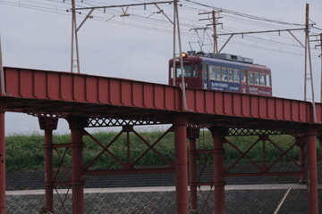 Obraz premium OSAKA, JAPAN - SEPTEMBER 2026: An electric tram crossing an old iron bridge over the Yamato River in Osaka.