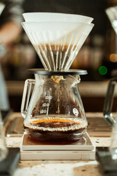 Coffee brewing process with pour-over coffee maker in a cafe setting