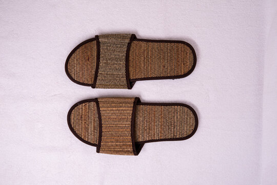 Indoor home decor with woven slippers on a pink background
