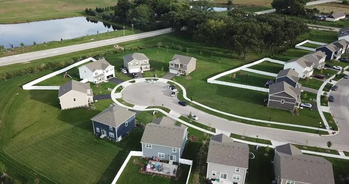 Aerial drone video of new houses in a rural subdivision neighborhood as the drone gets lower and the camera tilts up. 