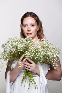 Young woman holding gypsophila baby's-breath bouquet in beauty skincare portrait studio photoshoot.