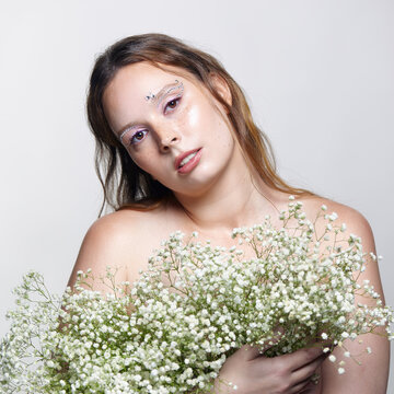 Young woman holding delicate baby's-breath gypsophila flowers against grey studio background