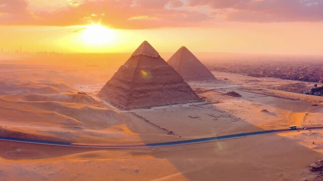 Aerial video view of pyramids at sunset, showcasing vast desert landscape and cityscape. Live desktop wallpaper.
