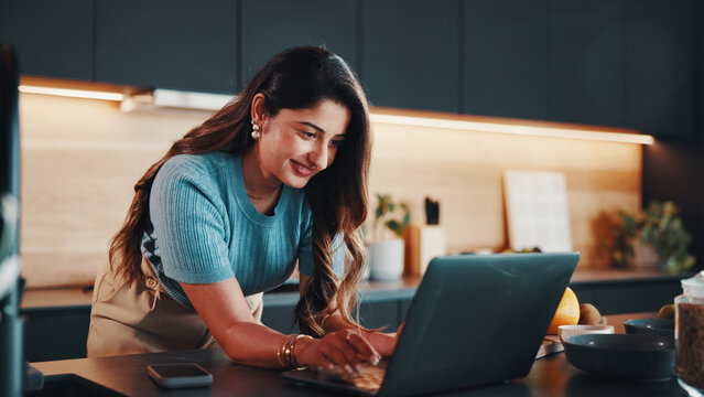 Businesswoman, smile and remote work in kitchen with laptop, typing email response or administration. Happy, contract worker and person in home with computer, administrator job and morning tasks.