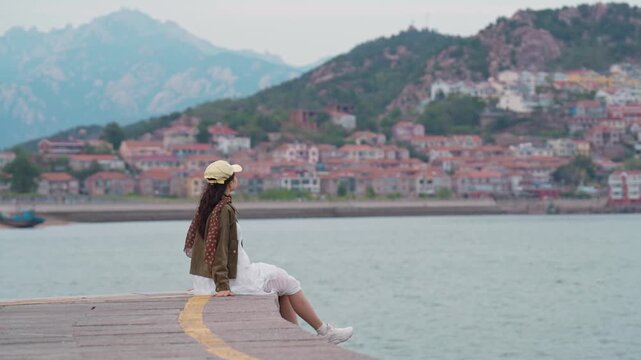 Female tourist relaxing and enjoying the scenic view of the fishing village along the coast at Shazikou in Qingdao