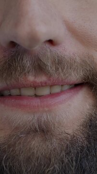 Close-up portrait of male mouth smiling while bearded man feeling happy on black color background. People and positive emotion concept.