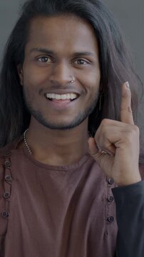 Portrait of Indian man thinking then raising finger having great idea looking at camera on black background. People and creative solutions concept.