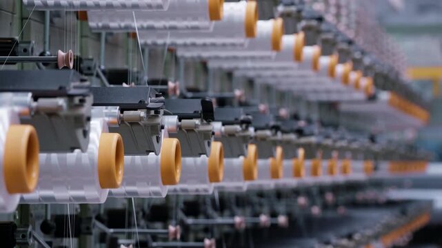 Industrial automation factory production line weaving plant of polypropylene bags yarn spools industrial. White reels with ropes making plastic sacks in a modern nylon manufacture enterprise