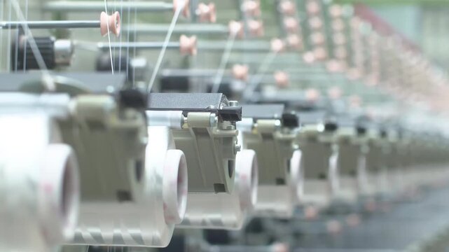 Industrial automation factory production line of weaving plant of polypropylene bags yarn spools industrial. White reels with ropes making plastic sacks in a modern nylon manufacture enterprise