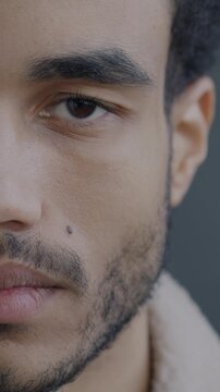 Close-up portrait of sad African American man half face looking at camera feeling unhappy on black studio background. Negative emotion and people concept.