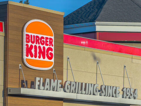 Calgary, AB, Canada. September 29, 2026. Exterior angle view of a Burger King restaurant building sign featuring flame grilling slogan text.