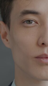 Close-up slow motion portrait of young man half face looking at camera on black color background. People and expression concept.
