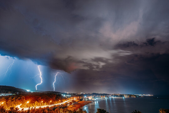 Thunderstorm Lightning Strike Over Coastal Town Bay at Night with Electric Flash