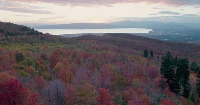 Aerial Shot Soaring Over Autumn Rocky Mountains With Lake in Distance At Sunset