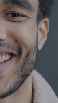 Close-up portrait of joyful African American man half face laughing looking at camera on black studio background. People and joy concept.