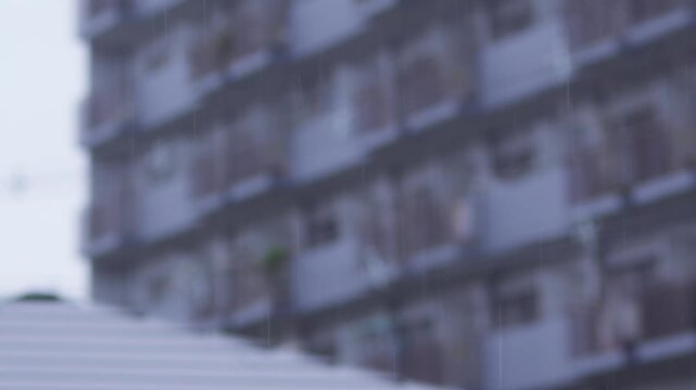 背の高いマンションを背景に住宅街に降る雨を捉えたスローモーション映像。ピント位置のバリエーション