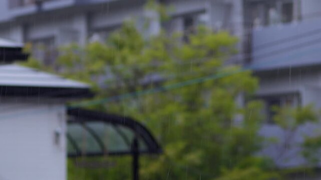 背の高いマンションを背景に住宅街に降る雨を捉えたスローモーション映像。ピント位置のバリエーション