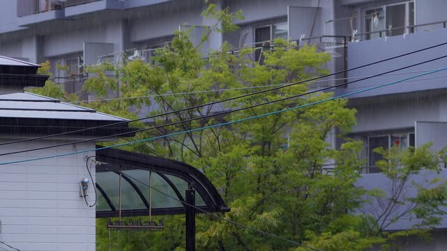 背の高いマンションを背景に住宅街に降る雨を捉えたスローモーション映像。ピント位置のバリエーション
