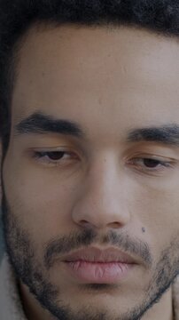 Close-up portrait of sad and gloomy African American man looking at camera on black studio background. People and negative emotion concept.