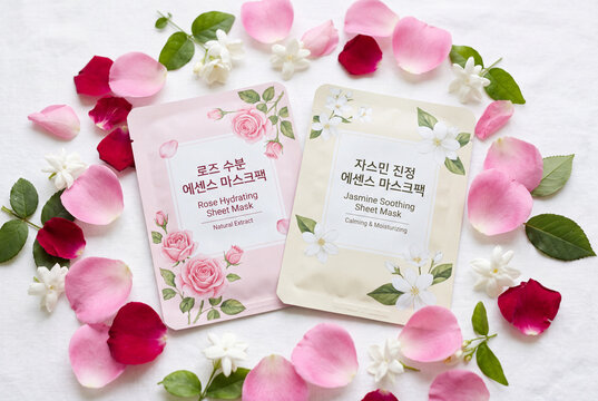 Rose and jasmine sheet face masks flatlay with petals and leaves on white surface for skincare banner and beauty product background design