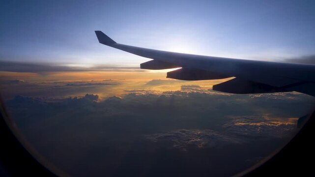 A Stunning Aerial View of Clouds and Sunset Behind an Airplane Wing Captured Through a Window, Emphasizing the Beauty of Air Travel and Nature's Palette