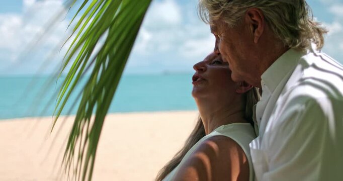 Happy senior couple relaxing on a tropical beach, embracing the warm sunshine and enjoying their retirement travel, with palm shadows adding serene atmosphere to their resort getaway. Samui, Thailand