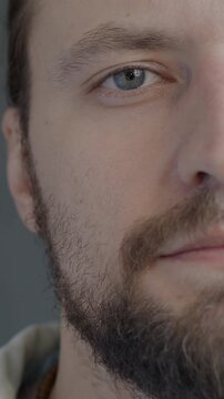 Close-up portrait of confident young man half face looking at camera with no emotion on black color background. People and expression concept.