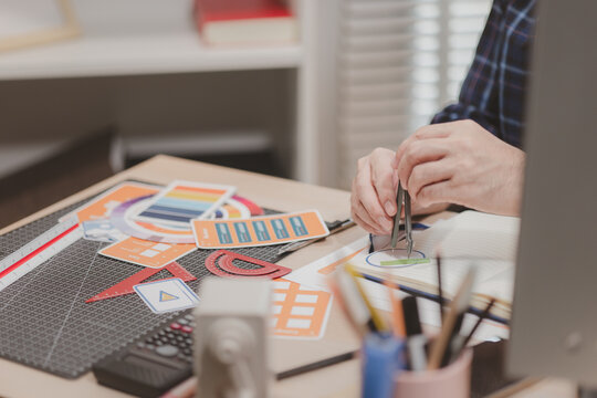 Designer working with color palettes, layout templates, and creative design tools on a desk while planning branding and graphic design projects in a modern office.
