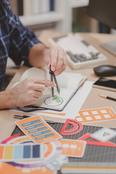 Designer working with color palettes, layout templates, and creative design tools on a desk while planning branding and graphic design projects in a modern office.