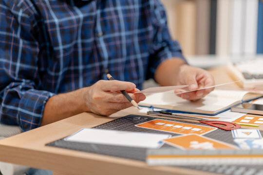 Designer arranging color swatches, layout samples, and branding materials on a creative workspace while planning a visual identity project with notebooks and design tools.