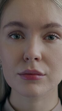 Slow motion portrait of beautiful young woman with blond hair looking at camera with serious face on black color background. People and emotion concept.