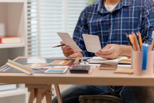 Designer arranging color swatches, layout samples, and branding materials on a creative workspace while planning a visual identity project with notebooks and design tools.