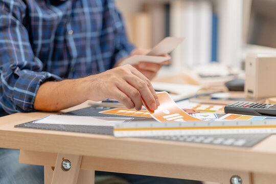 Designer arranging color swatches, layout samples, and branding materials on a creative workspace while planning a visual identity project with notebooks and design tools.