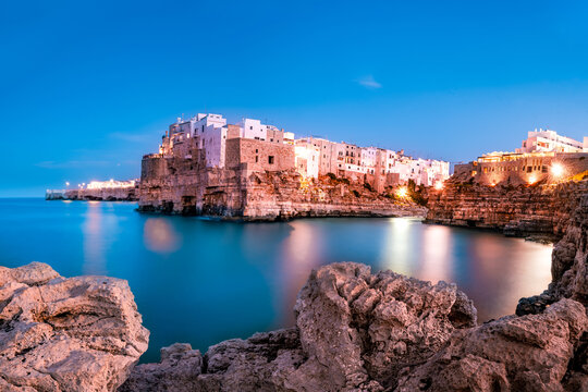 Whitewashed buildings on the limestone cliffs of Polignano a Mare at blue hour, Puglia, Italy