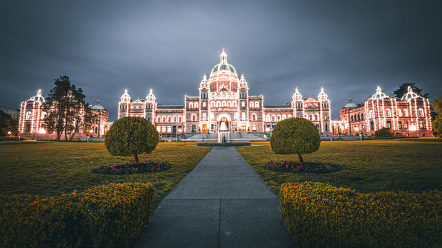 British Columbia Parliament Buildings glowing at dusk with a pathway and gardens, Victoria, BC, Canada