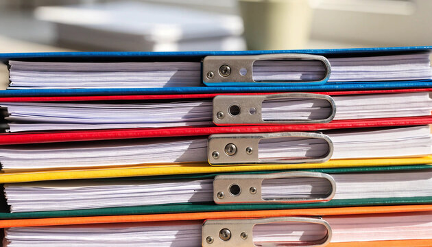 Stacked colorful binder metal clip office document paperwork close up organization business stationary horizontal sunlight workspace