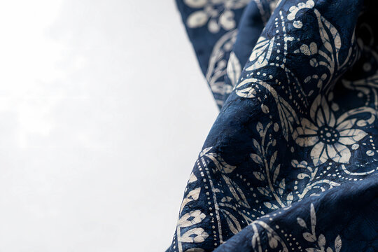 Close-up of indigo batik cloth with fine wax-resist patterns and visible cotton fibers, soft natural light, empty copy space on the left