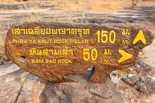 Wooden directional signpost pointing to Phra Ya Krut Rock Pillar and Sam Sao Rock
