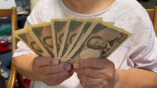 お札を広げてパタパタする女性