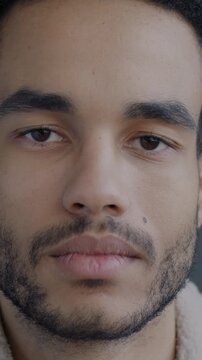 Slow motion portrait of serious African American man looking at camera on black background. Face expression and confident person concept.