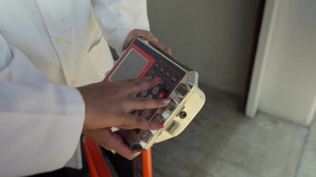 Close-up of a scientist's hands operating an industrial scale, weighing materials for sustainable construction and recycled plastic eco-brick development.