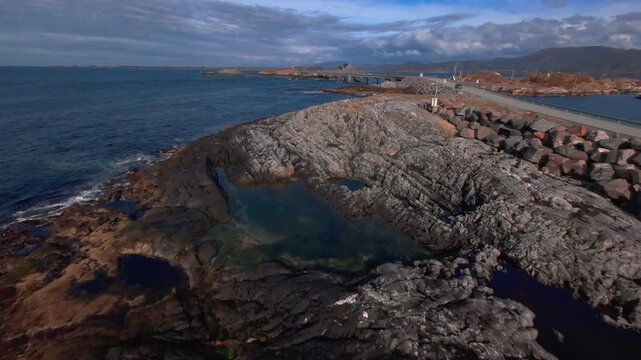 Aerial footage of the rocky coastline near the Atlantic Ocean Road in Norway, revealing rugged rock formations beside the Norwegian Sea.