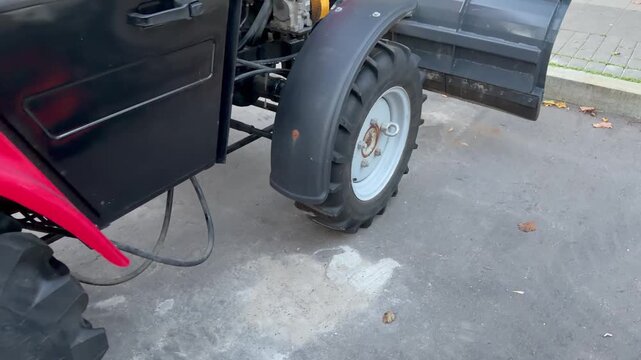 Close-up of rugged tractor tire and part of black metal frame on concrete ground, heavy machinery detail, industrial equipment concept.