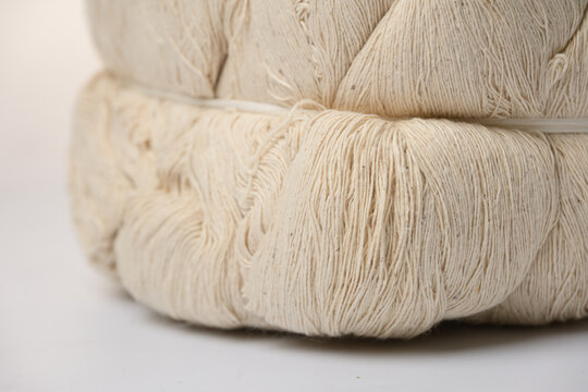 Raw cotton yarn natural fiber textile material close up beige color soft texture industry craft supply macro detail traditional handmade neutral background