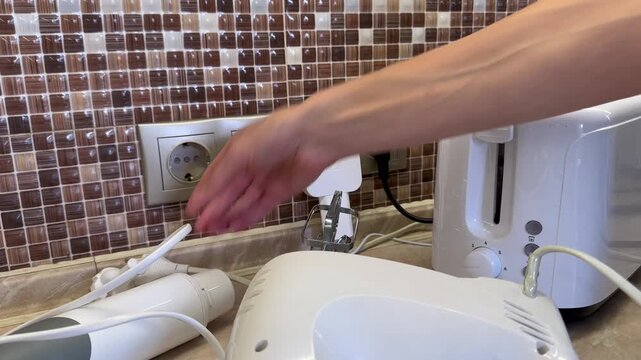 Hand unplugging all electrical appliances from wall outlets, disconnecting unused devices to reduce electricity consumption, conserve energy and save power at home.