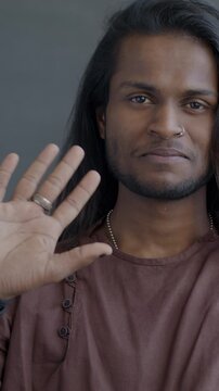 Slow motion portrait of friendly Indian man waving hand smiling looking at camera on black color background. People and expression concept.